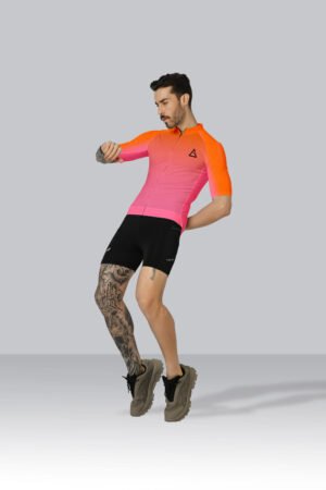 cyclist wearing Aidan Global’s Best Summer Cycling Jersey in vibrant orange-pink gradient with black cycling shorts, posing on a grey background